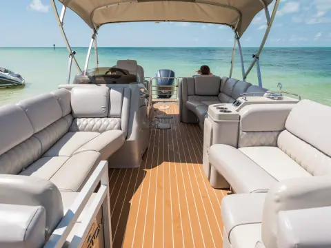 Luxury boat interior with beige seating under a canopy on a sunny day.
