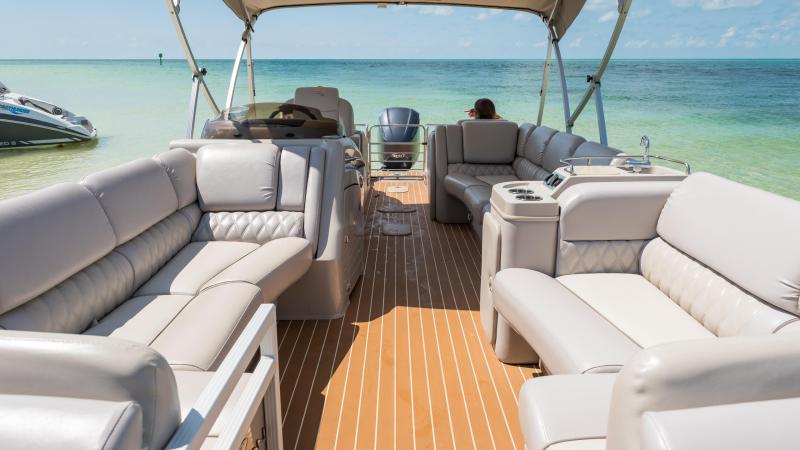 Luxury boat interior with beige seating under a canopy on a sunny day.