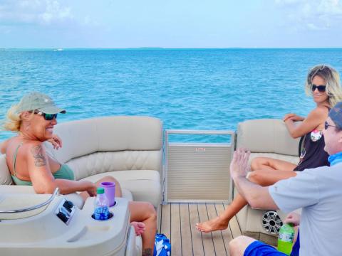 Three people relaxing on a boat, surrounded by a calm blue sea.