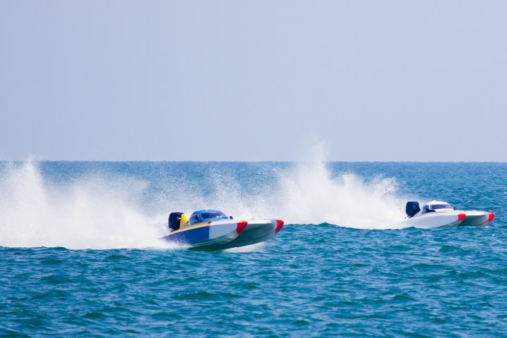 Two speedboats racing across the ocean, creating large splashes.