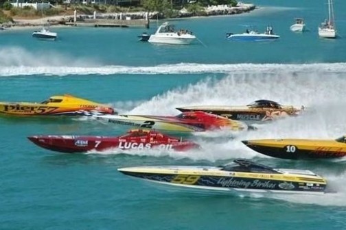 Speedboats racing on blue water with spectators on other boats.