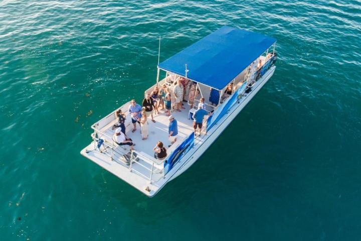 Boat with a blue canopy and people on calm blue water.