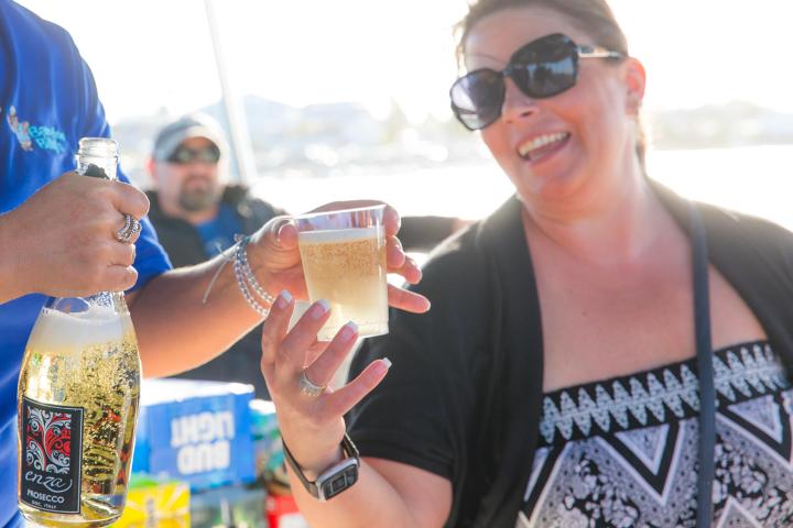 Person smiling while receiving a glass of champagne outdoors.