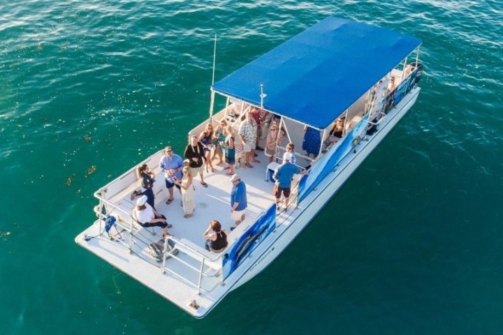 People gathered on a boat with blue canopy on open water.