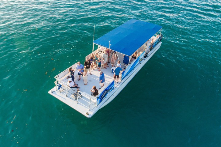 Aerial view of a boat with people on a blue-green sea.