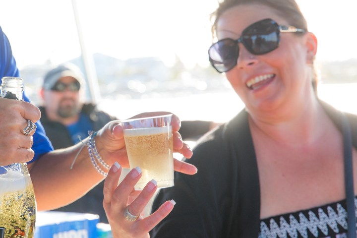 Smiling woman holding a cup of beverage being poured from a bottle.