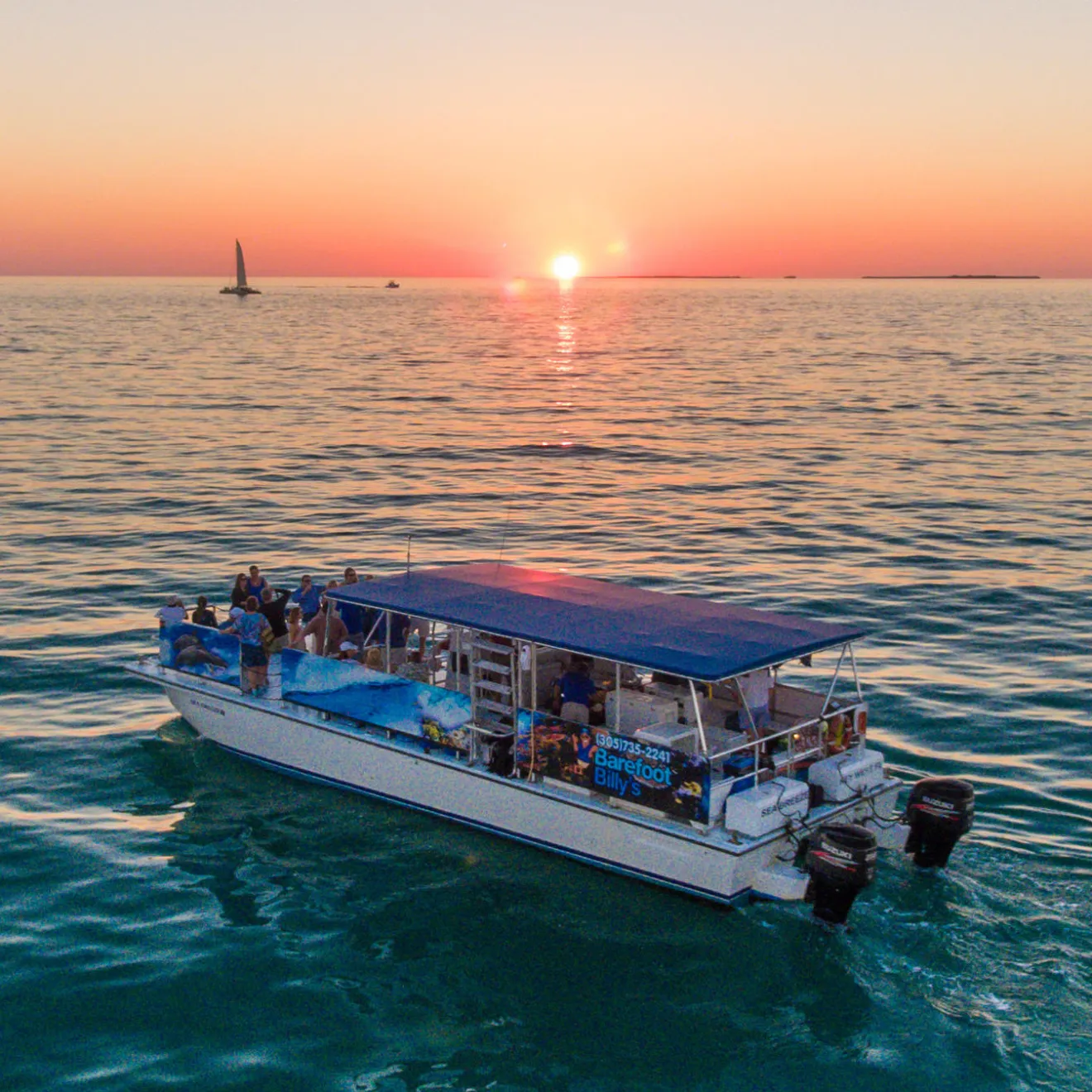 Boat on ocean at sunset with sailboat in distance.