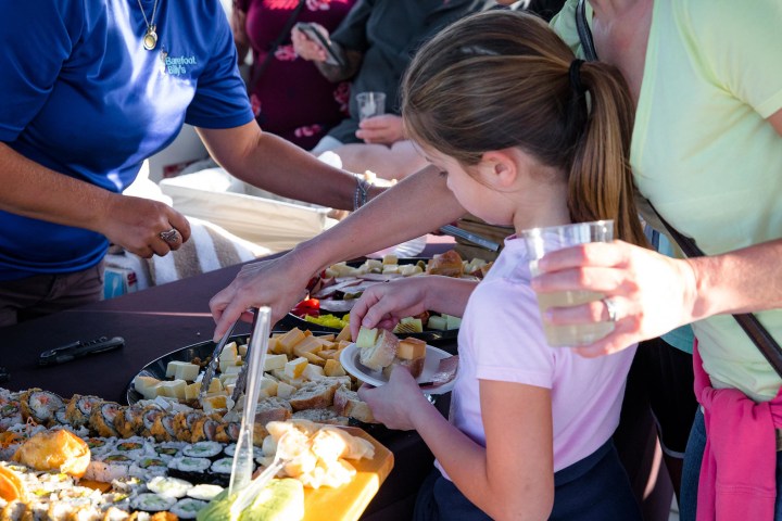 A child and adult selecting food from a buffet table.